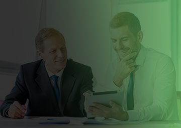 Two business men engaged in discussion at a table, utilizing a tablet for digital marketing strategies.