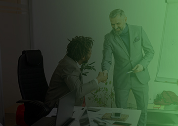 Two men shaking hands in an office, symbolizing a successful partnership in digital marketing and web design services.
